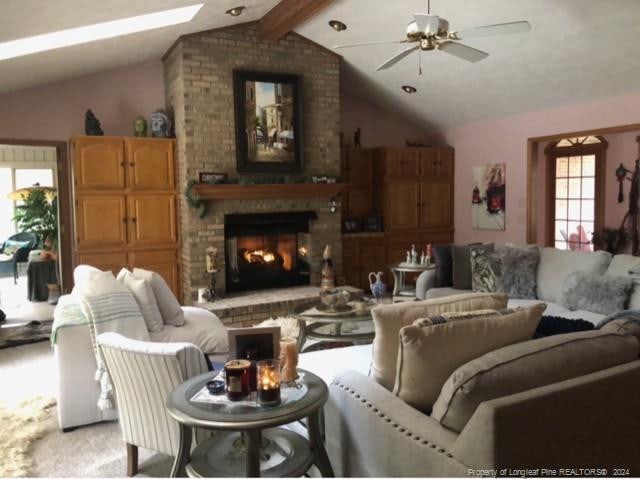 living room featuring lofted ceiling with beams, a fireplace, and ceiling fan