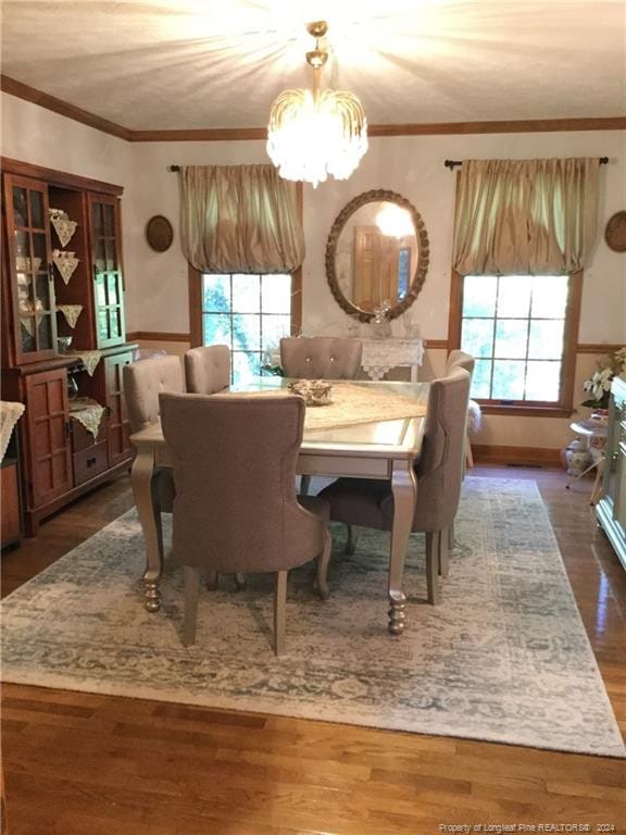 dining space with dark wood-style flooring, ornamental molding, and a chandelier