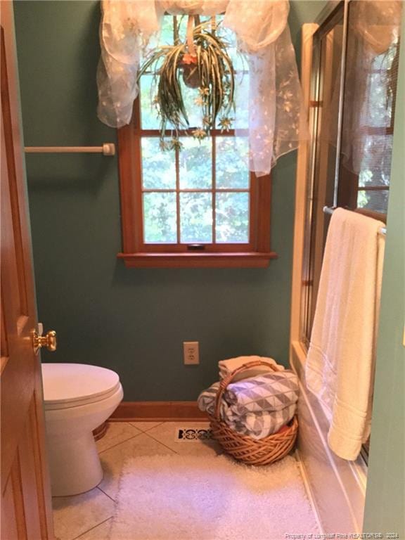 full bath featuring tile patterned flooring, toilet, baseboards, and an enclosed shower