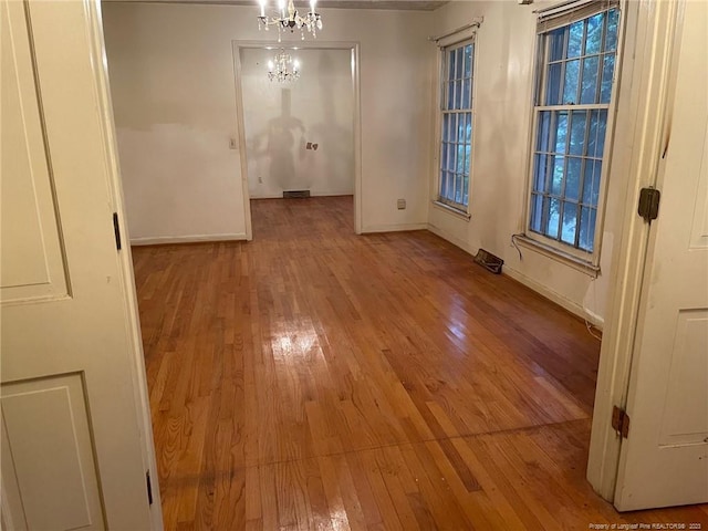 spare room featuring light hardwood / wood-style flooring and a chandelier