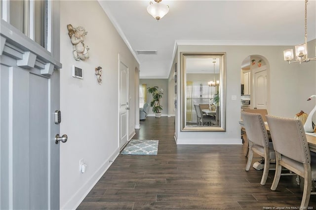 entryway with ornamental molding, a notable chandelier, and dark hardwood / wood-style flooring