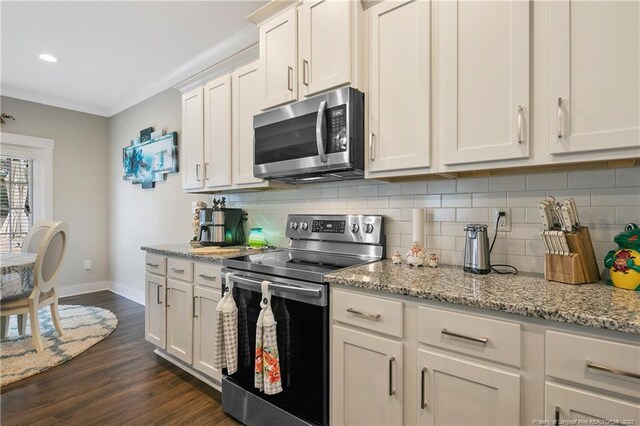 kitchen with backsplash, stainless steel appliances, dark wood-type flooring, light stone countertops, and white cabinetry