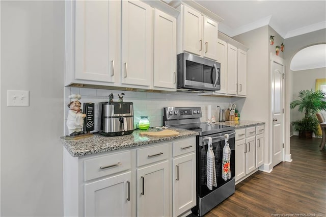 kitchen with dark hardwood / wood-style flooring, ornamental molding, stainless steel appliances, tasteful backsplash, and white cabinetry