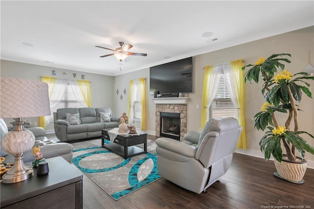 living room with plenty of natural light, a stone fireplace, ceiling fan, and dark hardwood / wood-style flooring