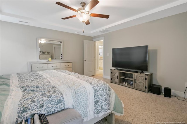 carpeted bedroom with ceiling fan and a tray ceiling