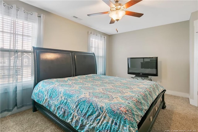 bedroom with ceiling fan, light colored carpet, and multiple windows