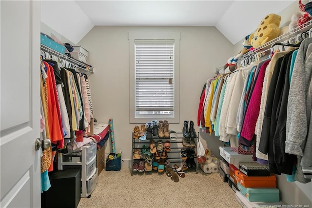 walk in closet with light colored carpet and lofted ceiling