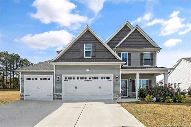 craftsman house with covered porch, a front lawn, and a garage