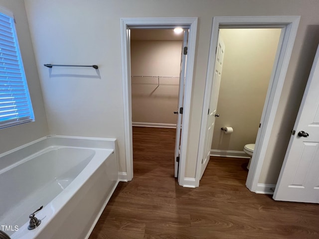 bathroom featuring hardwood / wood-style flooring, a washtub, and toilet