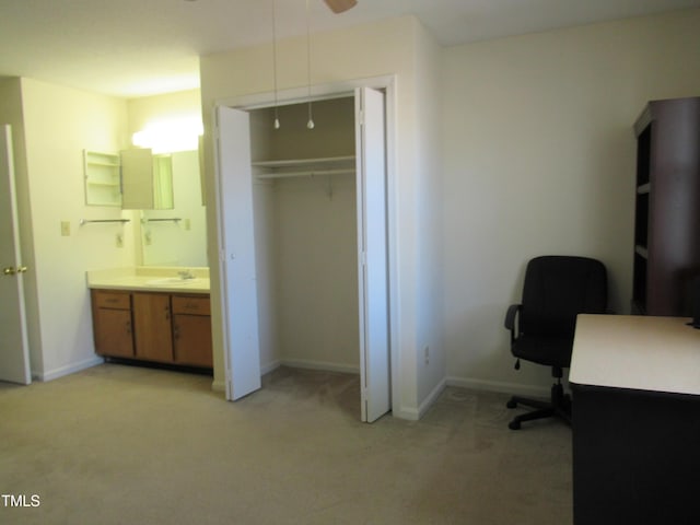 interior space featuring light colored carpet, a sink, and baseboards