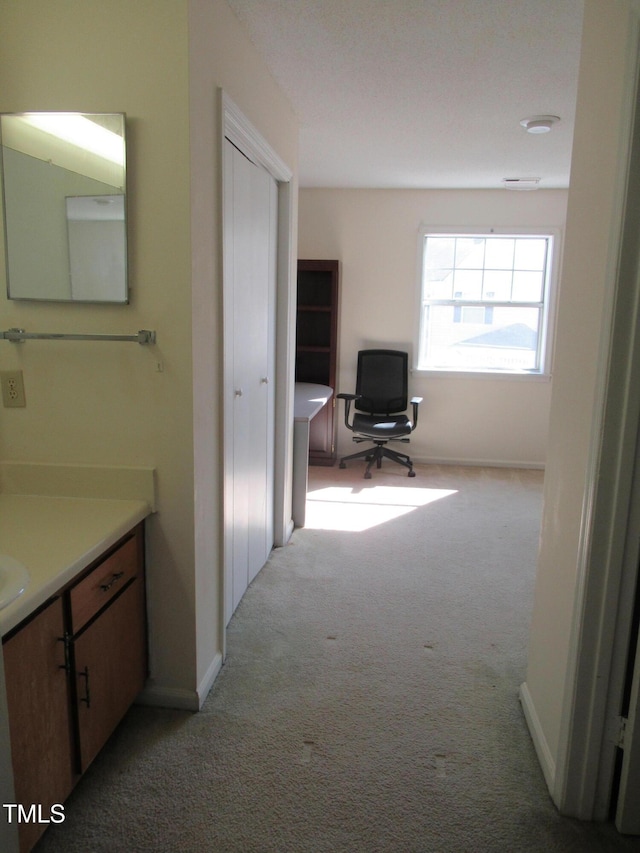 hall with baseboards and light colored carpet