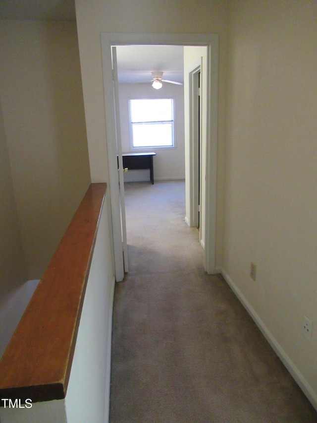 hallway with baseboards, light carpet, and an upstairs landing