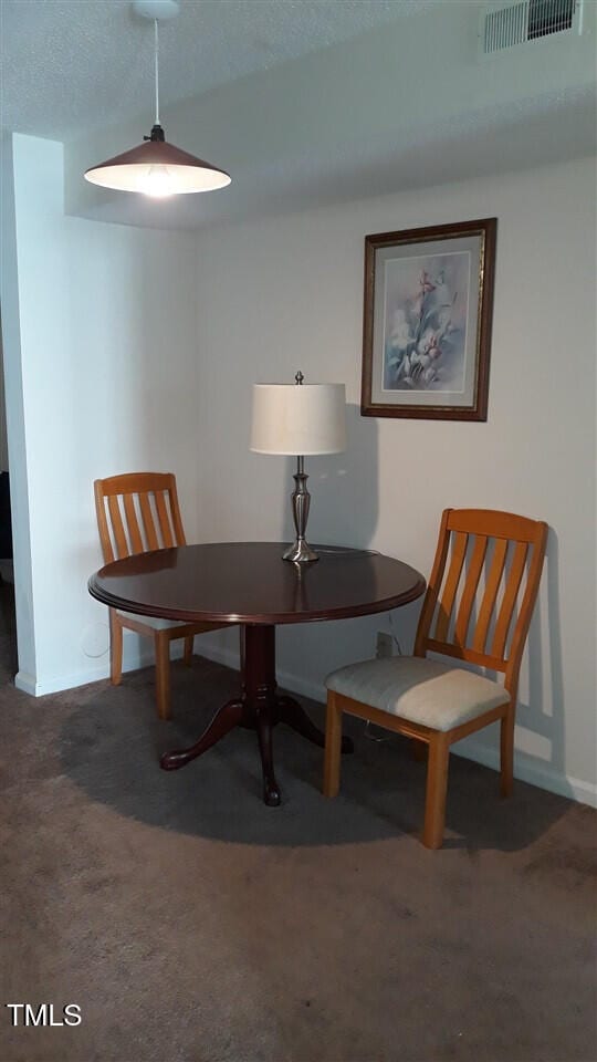 carpeted dining room featuring visible vents and baseboards