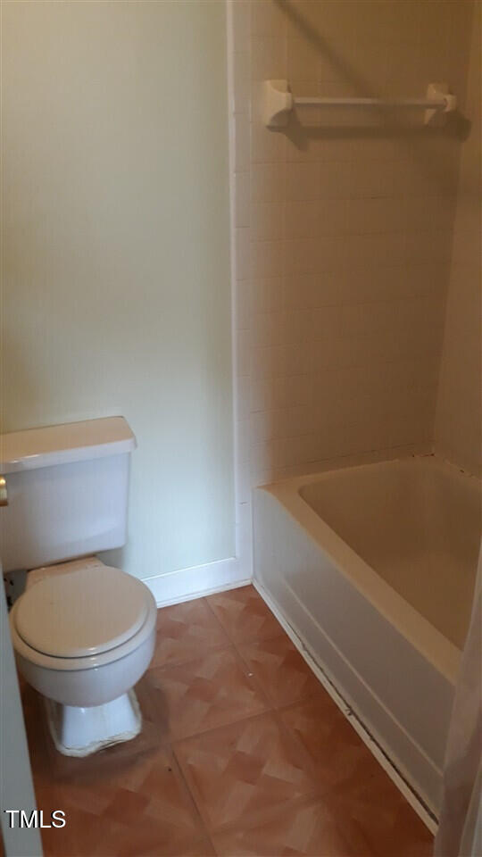 bathroom featuring baseboards, bathing tub / shower combination, and toilet