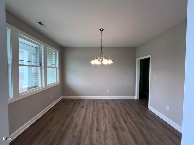 empty room featuring an inviting chandelier and dark hardwood / wood-style flooring