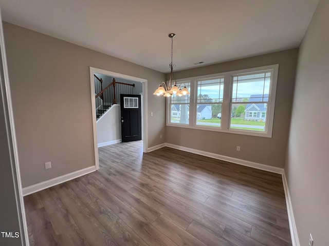 unfurnished dining area featuring a notable chandelier and hardwood / wood-style floors