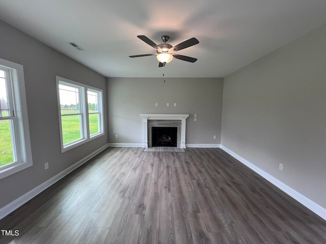 unfurnished living room featuring wood-type flooring, ceiling fan, and a tile fireplace