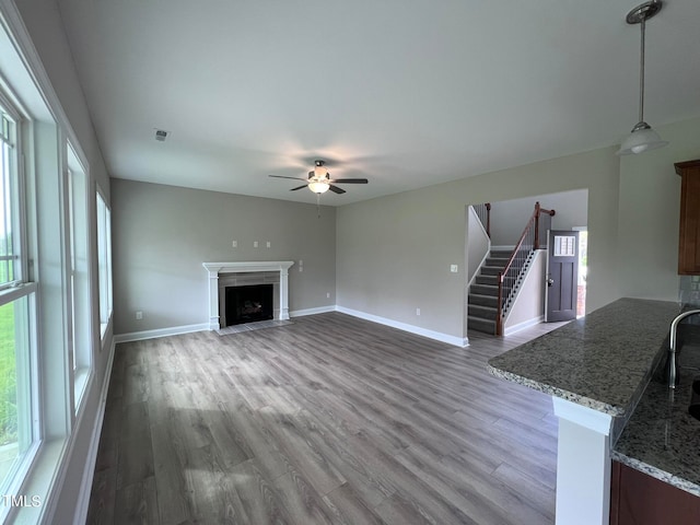 unfurnished living room featuring ceiling fan, plenty of natural light, and hardwood / wood-style floors