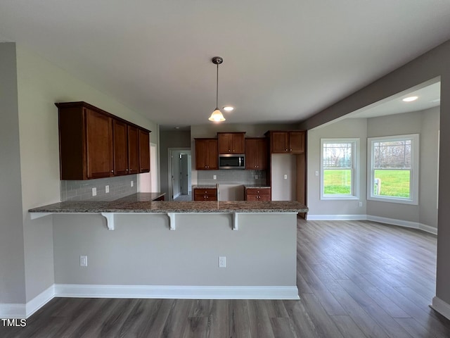 kitchen with decorative light fixtures, dark hardwood / wood-style floors, kitchen peninsula, and a breakfast bar