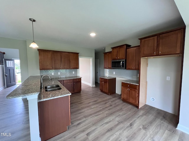 kitchen with sink, decorative light fixtures, light wood-type flooring, and kitchen peninsula