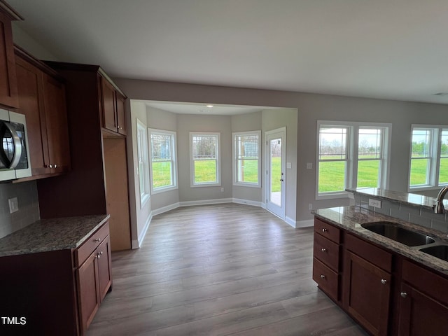 kitchen featuring decorative backsplash, dark stone countertops, light hardwood / wood-style floors, and sink