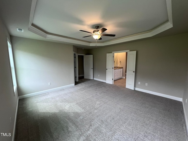 unfurnished bedroom with ornamental molding, a tray ceiling, ceiling fan, and light carpet