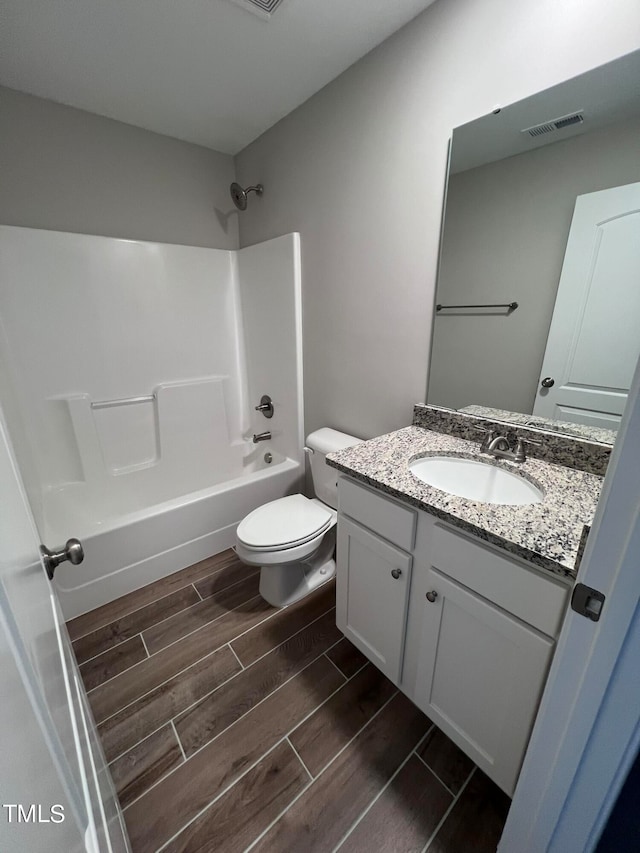 full bathroom featuring hardwood / wood-style floors, tub / shower combination, vanity, and toilet