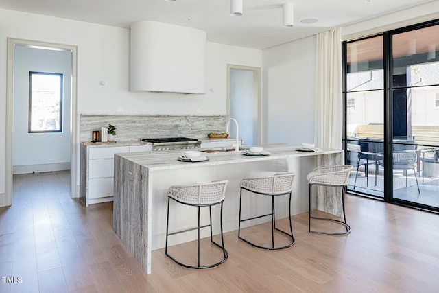 kitchen featuring white cabinetry, a wealth of natural light, stove, and light wood-type flooring