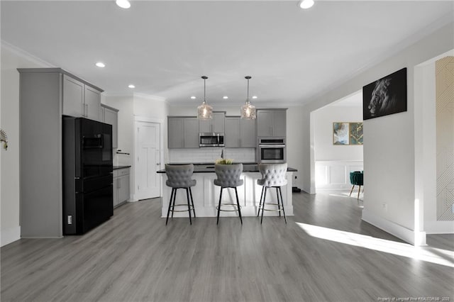 kitchen with tasteful backsplash, a kitchen breakfast bar, light wood-type flooring, gray cabinets, and stainless steel appliances