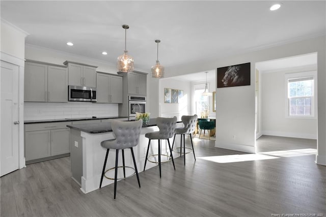 kitchen featuring a kitchen island with sink, gray cabinetry, stainless steel appliances, and light wood-type flooring