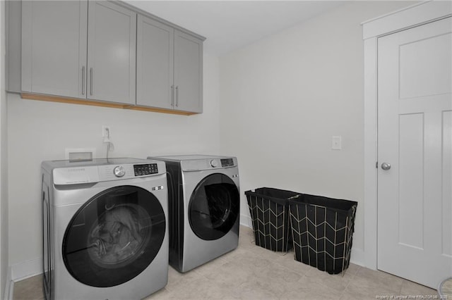 clothes washing area featuring separate washer and dryer and cabinets