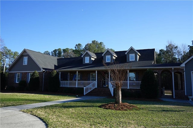 cape cod-style house featuring covered porch and a front lawn