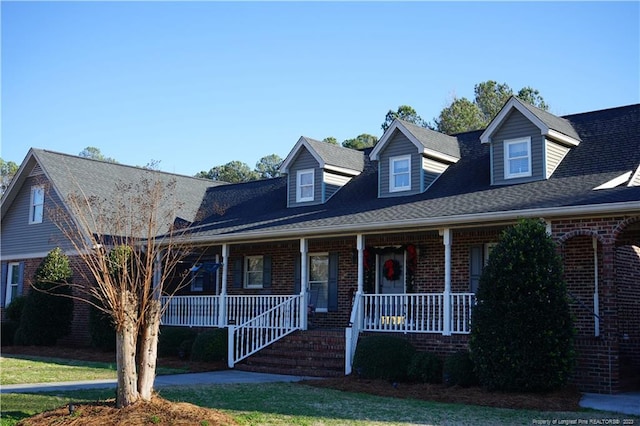 cape cod home with a front lawn and covered porch