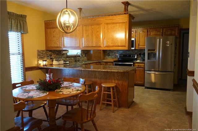 kitchen featuring appliances with stainless steel finishes, decorative light fixtures, tasteful backsplash, sink, and kitchen peninsula