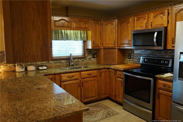 kitchen featuring stainless steel appliances, sink, decorative backsplash, and stone counters