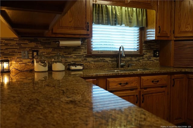 kitchen featuring sink, decorative backsplash, and dark stone countertops