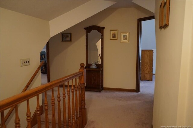 corridor with vaulted ceiling and light colored carpet