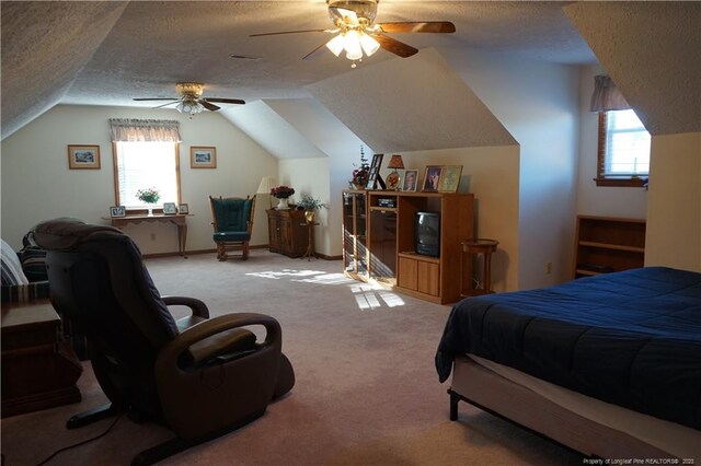 carpeted bedroom with multiple windows, vaulted ceiling, a textured ceiling, and ceiling fan