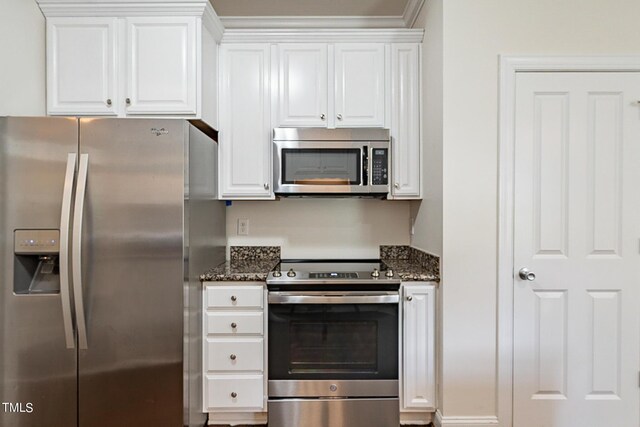 kitchen featuring appliances with stainless steel finishes, dark stone counters, and white cabinets