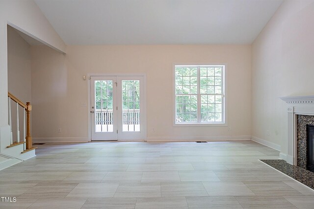 unfurnished living room featuring light tile patterned floors, a fireplace, plenty of natural light, and vaulted ceiling