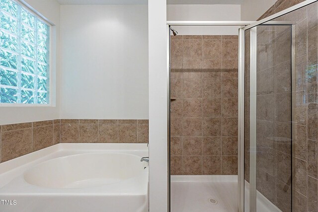 bathroom with shower with separate bathtub and plenty of natural light