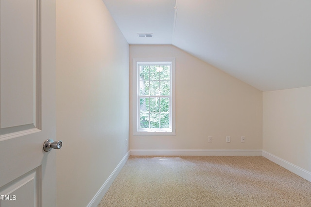 bonus room with lofted ceiling and light carpet