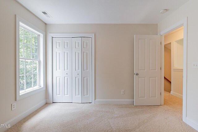 unfurnished bedroom with light carpet and a closet