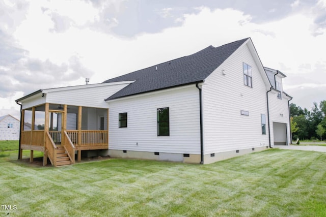 back of house with a garage, a lawn, and a sunroom