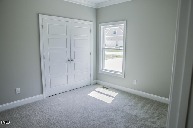 unfurnished bedroom with carpet floors, crown molding, and a closet