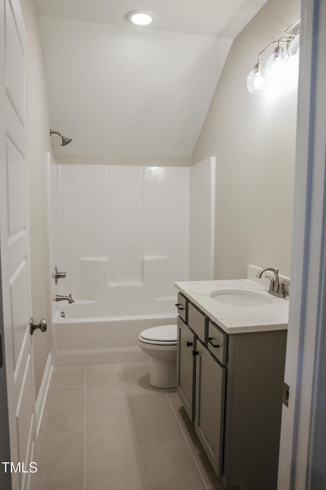 full bathroom featuring tile patterned flooring, tub / shower combination, lofted ceiling, toilet, and vanity