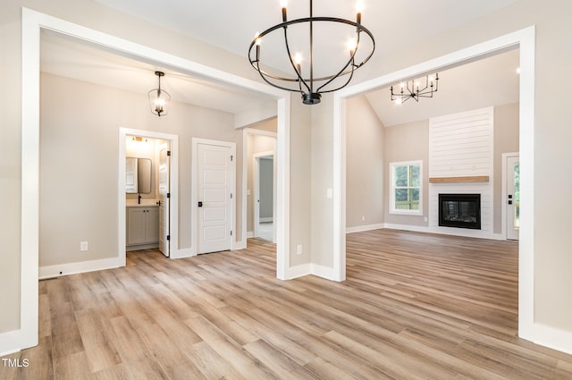 7327 Shawan Rd, Wendell, NC 27591 - unfurnished living room with a chandelier, light wood-type flooring, baseboards, a large fireplace, and lofted ceiling