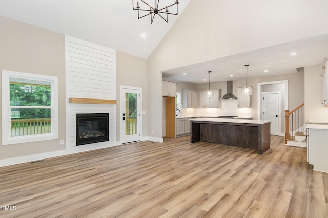 7327 Shawan Rd, Wendell, NC 27591 - kitchen featuring wall chimney range hood, light countertops, open floor plan, high vaulted ceiling, and a kitchen island