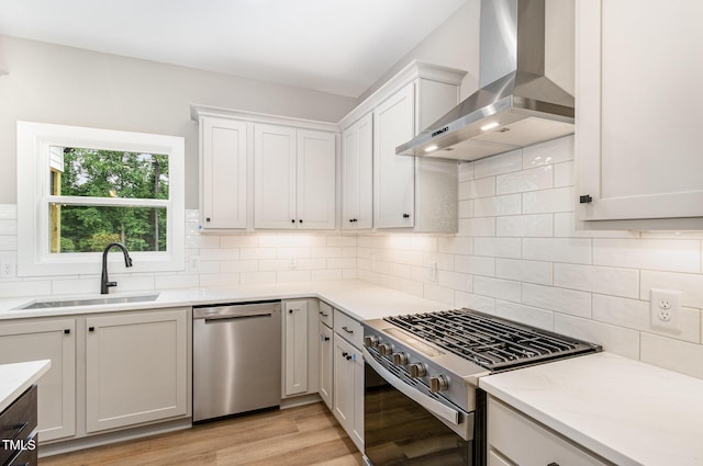 7327 Shawan Rd, Wendell, NC 27591 - kitchen with stainless steel appliances, wall chimney range hood, a sink, light wood-style flooring, and tasteful backsplash