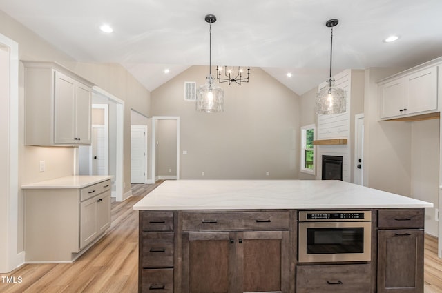 7327 Shawan Rd, Wendell, NC 27591 - kitchen with vaulted ceiling, light wood-style flooring, a fireplace, a chandelier, and baseboards
